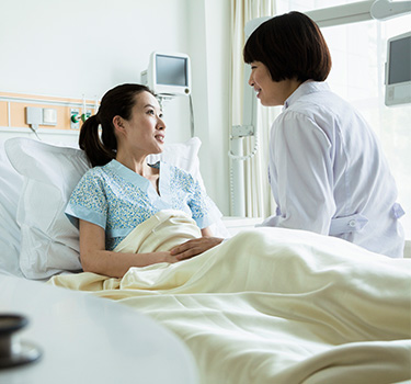 Asian female patient in hospital bed with doctor
